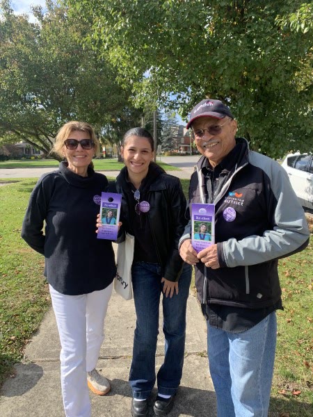 Anna Hopkins with two canvassers holding Re-elect Anna Hopkins door hangers on a neighbourhood sidewalk